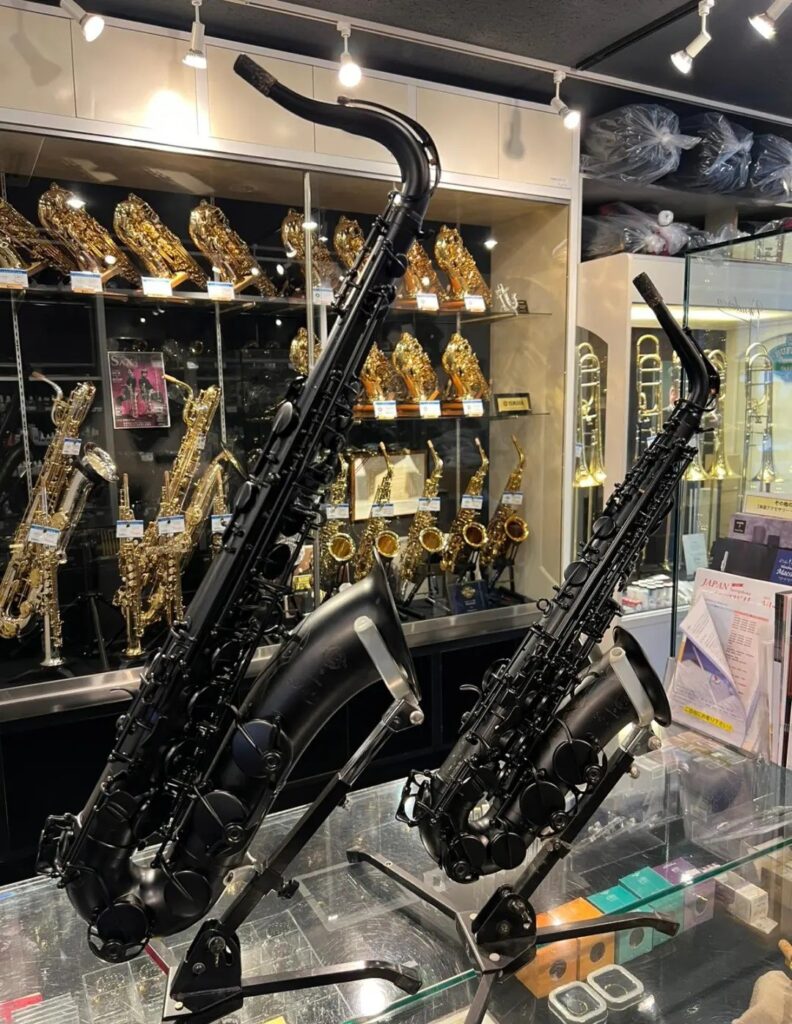 Saxofones pretos e dourados em suportes numa loja de música