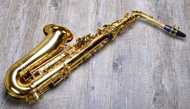 Saxofone tenor dourado sobre um piso de madeira